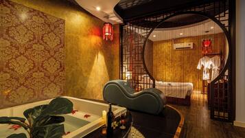 A spa room with a bathtub, a massage chair, and a separate area with a bed and a wall-mounted air conditioner.