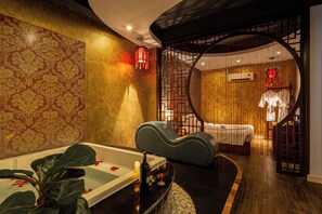A spa room with a bathtub, a massage chair, and a separate area with a bed and a wall-mounted air conditioner. - La Doma en Amour Hotel (Ho Chi Minh City)
