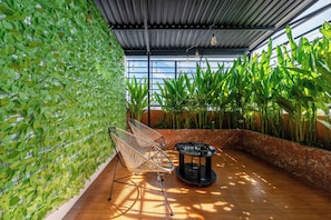 A room with a wall covered in green foliage, a seating area with a chair and a table, and tall plants against the wall. - La Doma en Amour Hotel (Ho Chi Minh City)