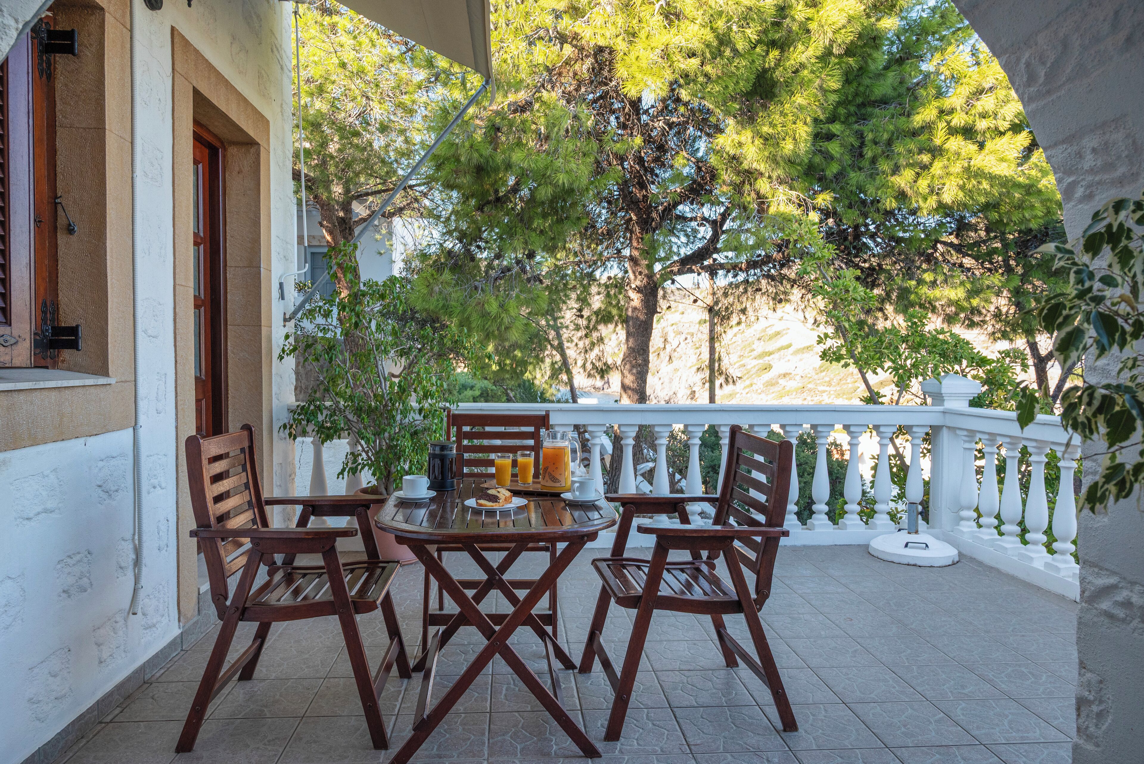 Un patio con una mesa, sillas, una planta en maceta y una barandilla.