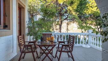Un patio con una mesa, sillas, una planta en maceta y una barandilla.