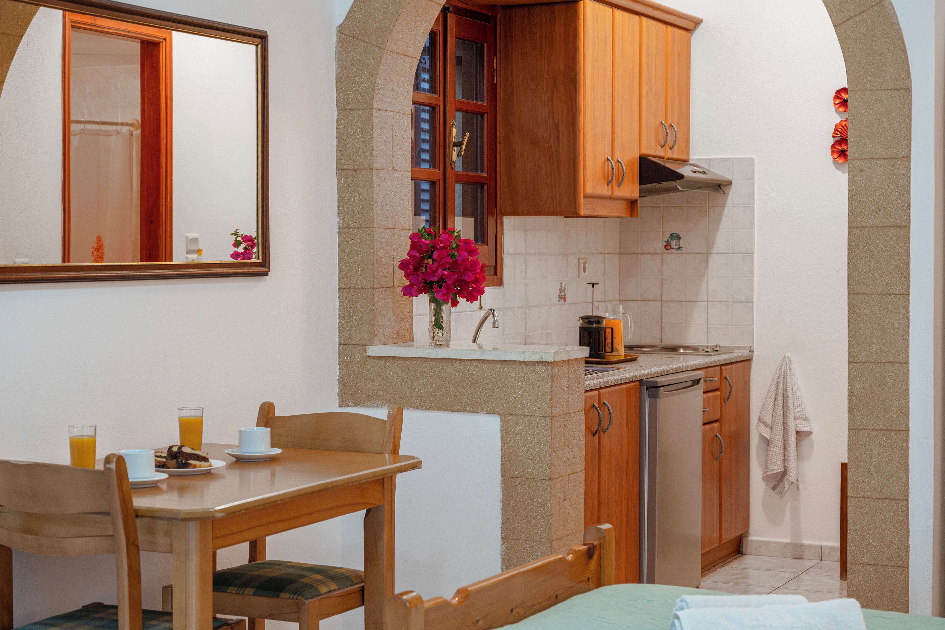 Una cocina compacta con armarios de madera, un lavamanos y un pequeño comedor con mesa y sillas.