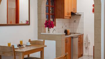 Una cocina compacta con armarios de madera, un lavamanos y un pequeño comedor con mesa y sillas.