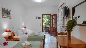 Quarto de hotel com duas camas, uma mesa de madeira, televisão e vista para o exterior.