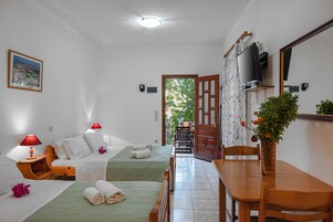 Habitación de hotel con dos camas, una mesa de madera, un televisor y vistas al exterior.