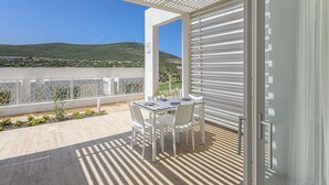 Un balcon avec une table et des chaises, une vue sur un paysage verdoyant et une balustrade blanche.