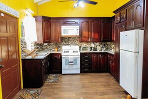 Una cucina con mobili in legno, un piano cottura bianco e un forno a microonde.