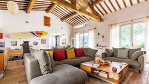 A cozy living room with a large sectional sofa, a coffee table, and a surfboard on the wall. - Magnificent villa with swimming pool and view of Saint Paul de Vence (Saint-Paul-de-Vence)