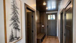 Un pasillo con paredes de madera, un banco y una puerta con ventanal.