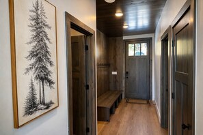 Un couloir aux murs en bois, avec un banc et une porte dotée d’une fenêtre.