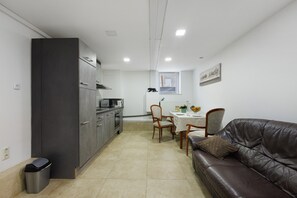 A compact kitchen with a dining area, a sofa, and a trash bin. - Apartment 'Tiefer Garten' with Wi-Fi (Itzehoe)