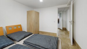 Een slaapkamer met twee bedden, een kledingkast en een badkamer, zichtbaar door een open deur.