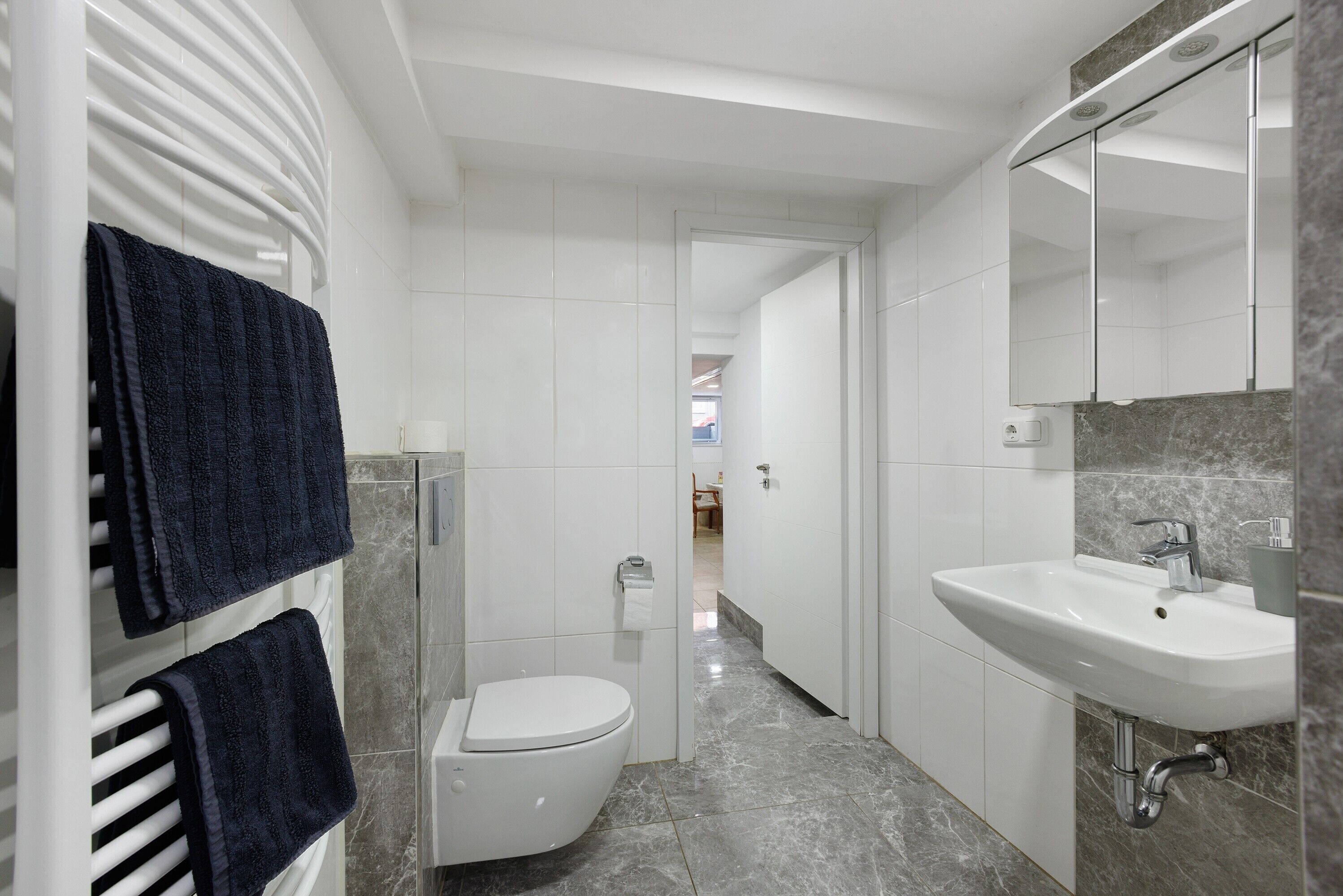 Une salle de bain moderne équipée de toilettes, d’un lavabo et d’un porte-serviettes.