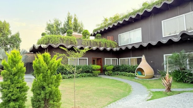 Un bâtiment moderne doté d’un chemin sinueux, d’un petit jardin et d’une structure sphérique originale.