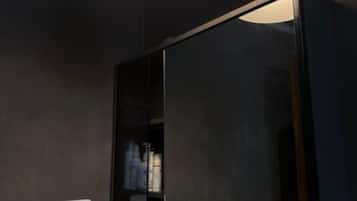 Um banheiro moderno com um espelho grande, uma luminária redonda e uma prateleira com artigos de higiene pessoal.