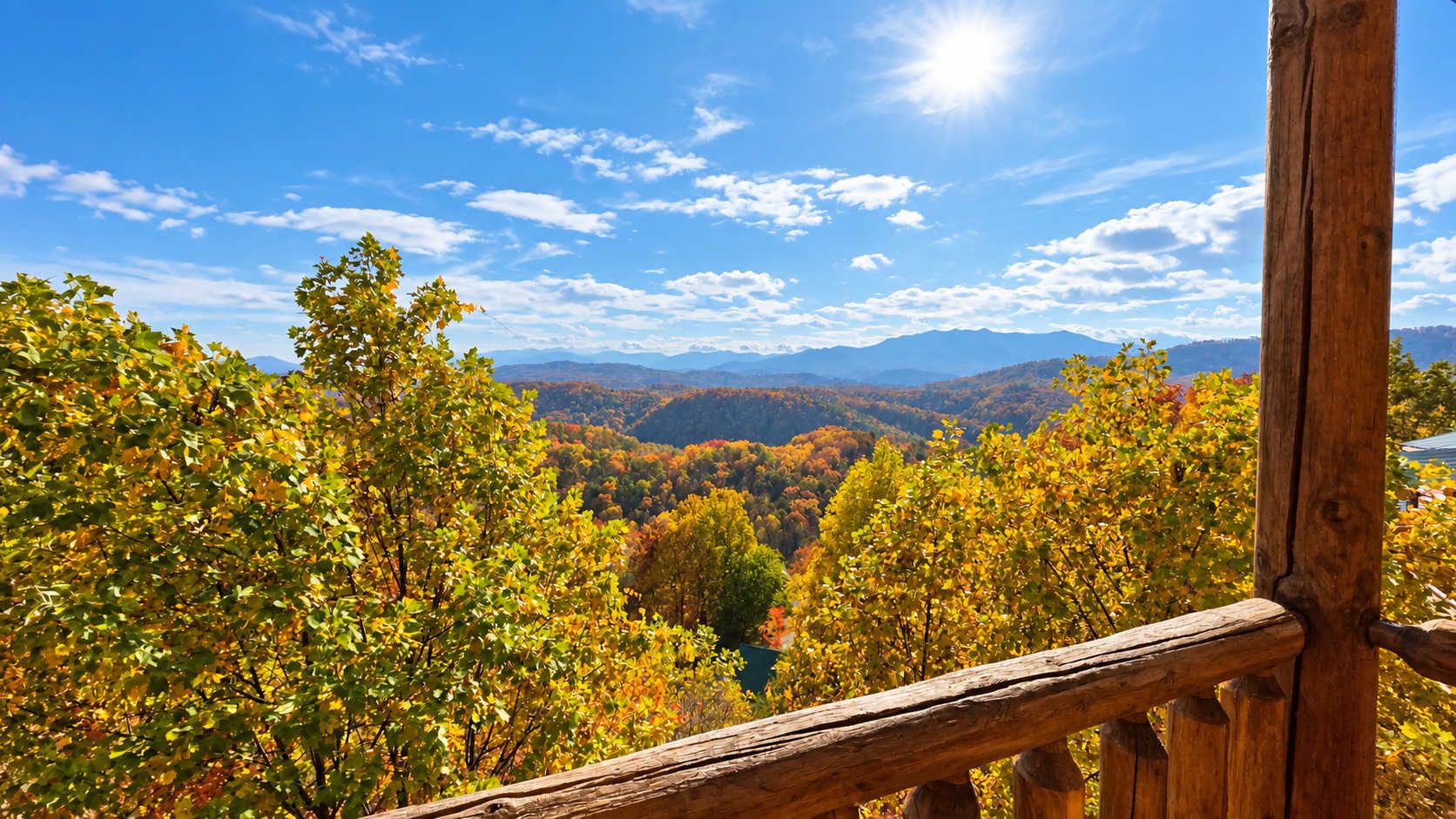A wooden railing overlooking a forested valley with a clear sky.