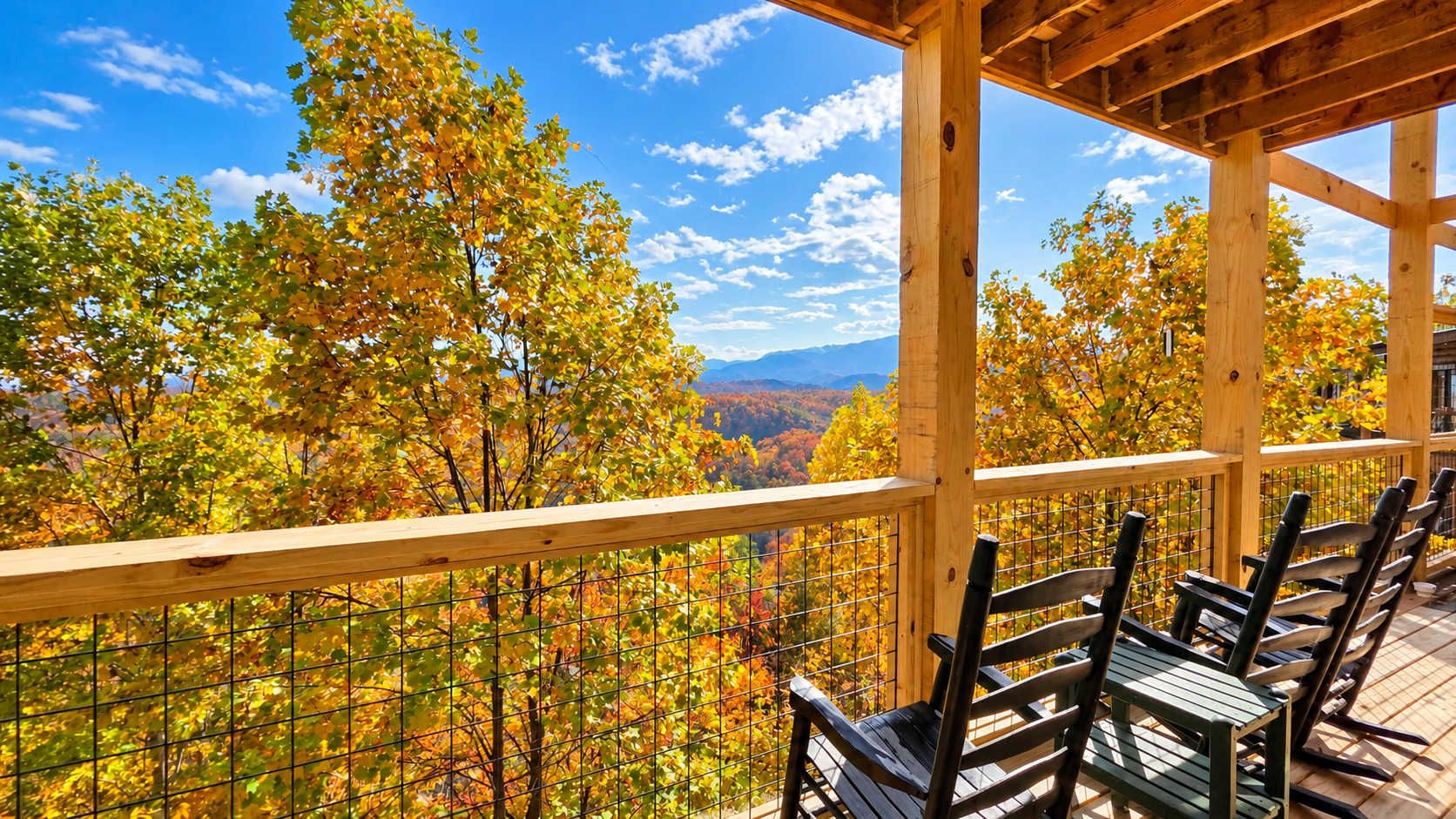 A wooden deck with chairs overlooking a forested landscape.