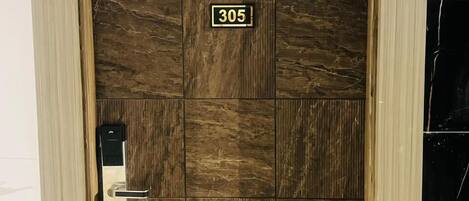 A wooden door with a number plate '305' and a keypad lock.