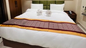 A hotel room with a large bed, two wall-mounted lamps, a framed artwork above the bed, and a telephone on the nightstand. - HOTEL SUPREME INN (Varanasi)