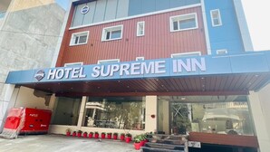 A hotel named "Hotel Supreme Inn" with a modern facade, large windows, and a covered entrance area with potted plants. - HOTEL SUPREME INN (Varanasi)