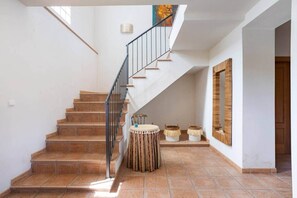 A staircase with a metal railing leading to a landing with a round table and decorative baskets. - Rural house on the edge of the Verde river (Tibi)
