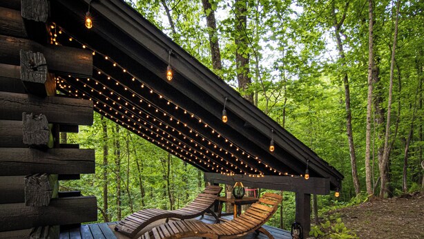 A wooden deck with string lights, a bench, and a table. - Lover’s Stone • Cliffside Hot Tub + Sauna + Cinema + Fireplace + Firepit (Blue Ridge)