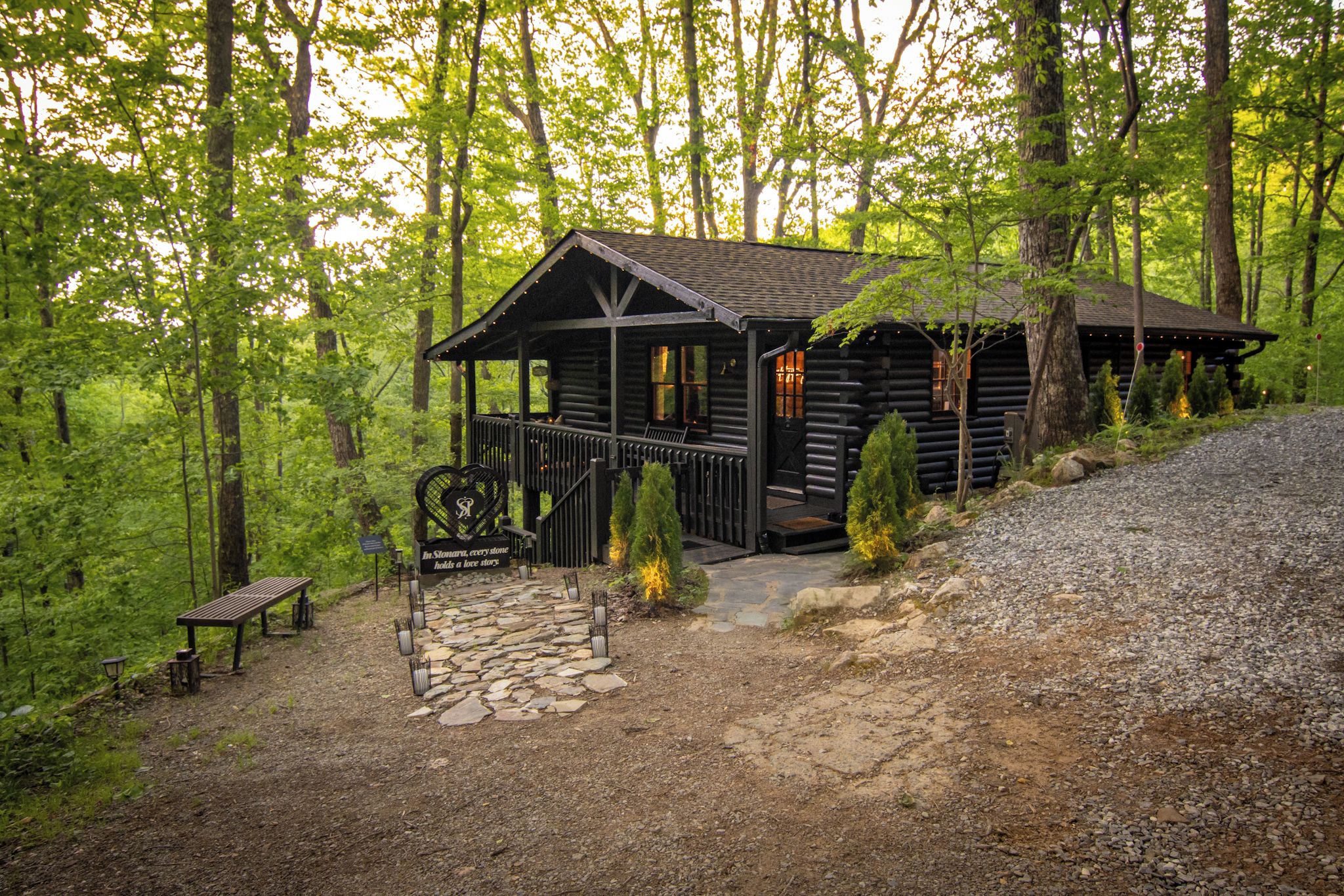 A rustic cabin with a porch, stone pathway, and a bench.