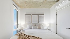 A bedroom with a large bed, a window, and three framed documents on the wall.