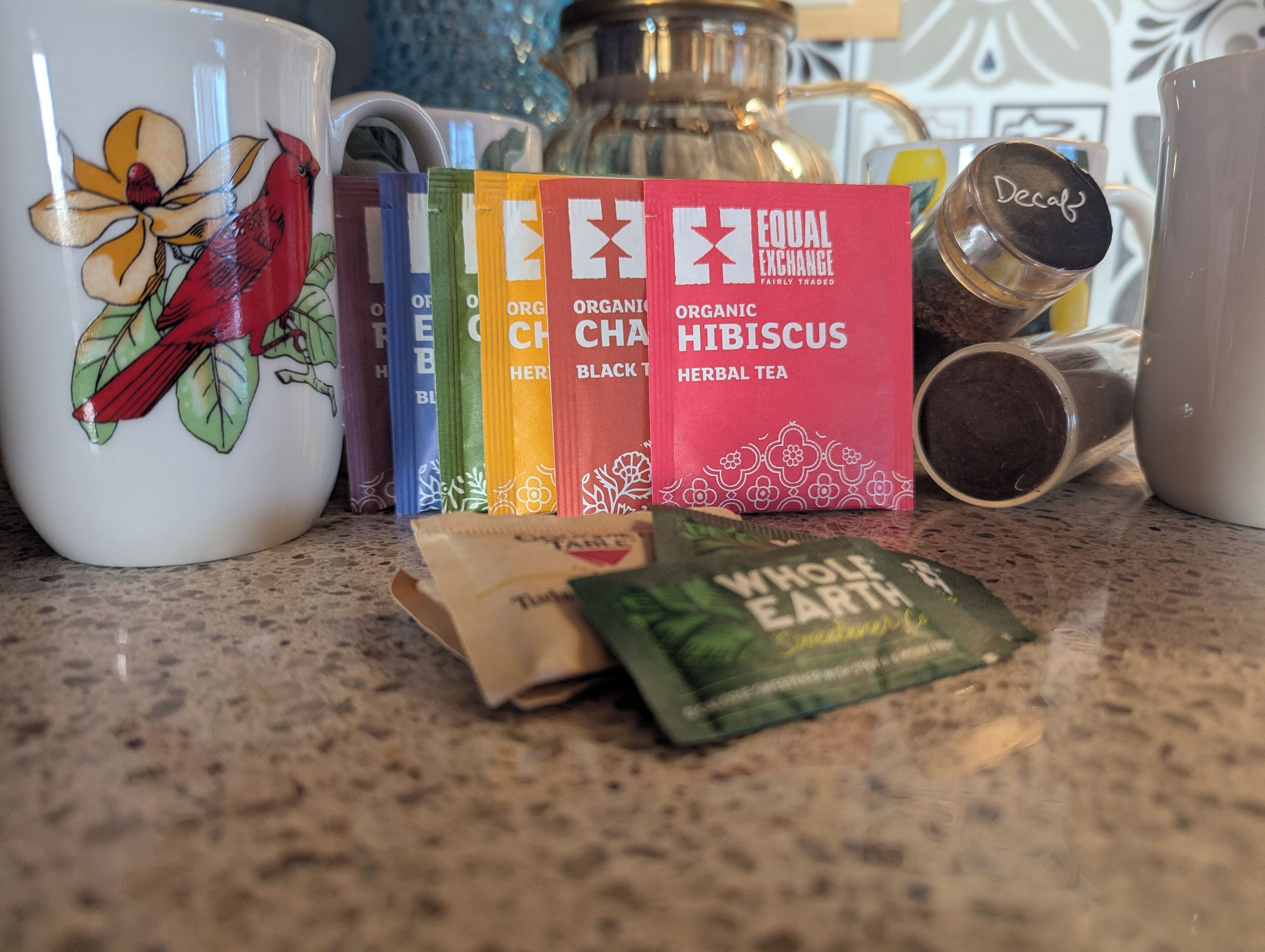 A kitchen counter with various tea bags and a coffee maker.