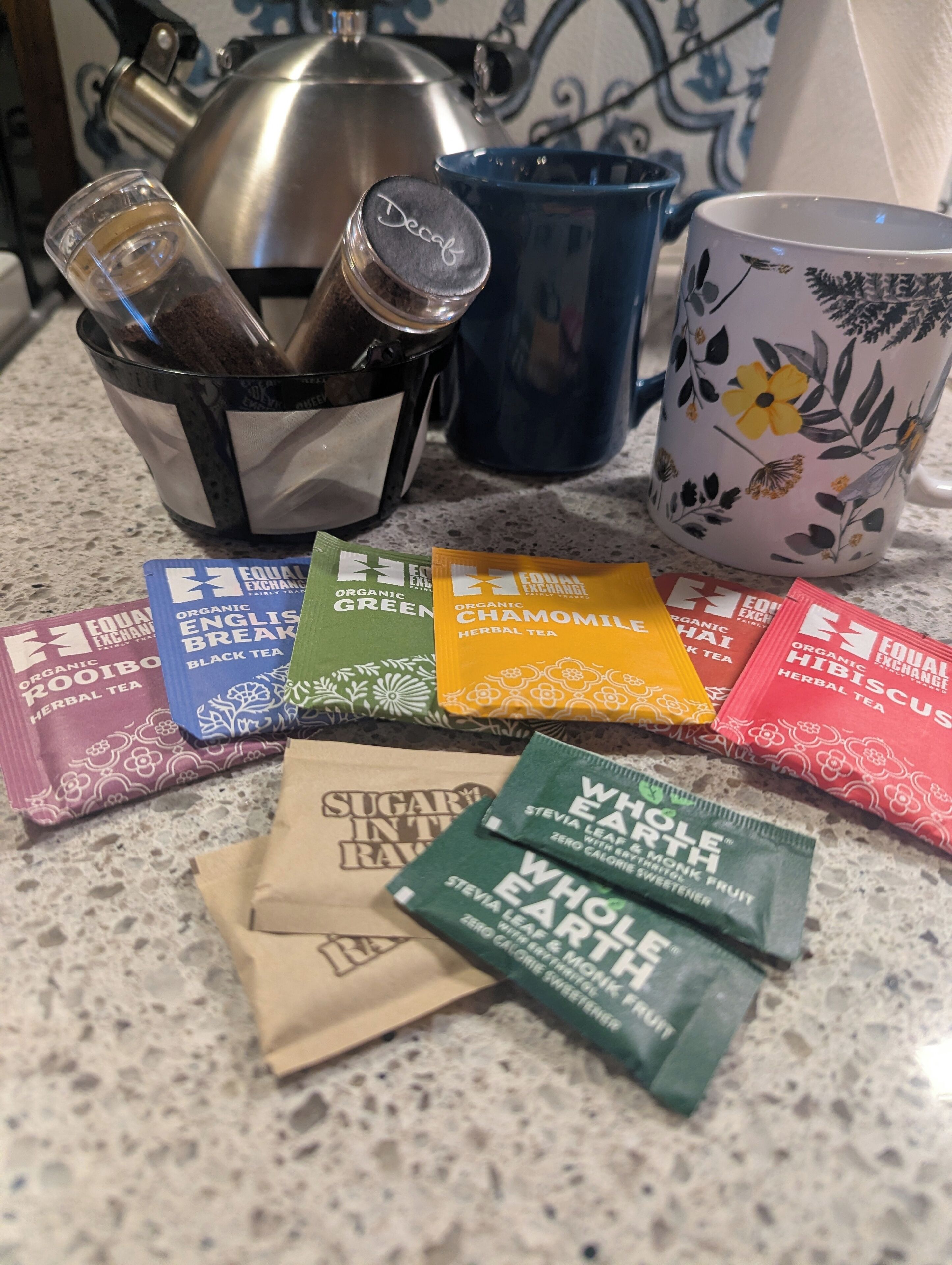 A kitchen counter with various tea packets and a kettle.