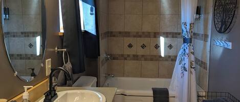Un baño con lavamanos, inodoro, ducha y bañera.
