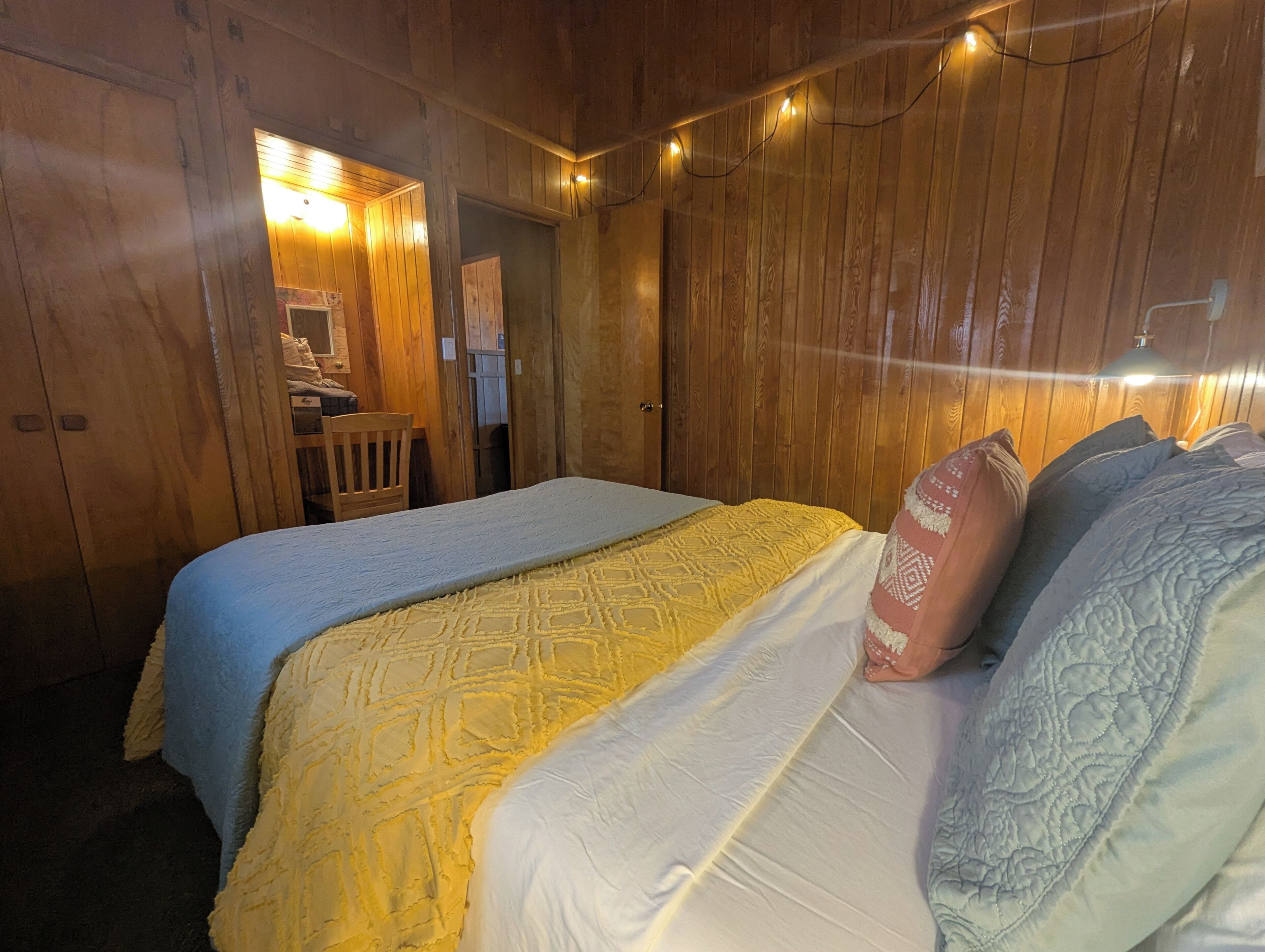 Een houten kamer met twee bedden, een stoel en een bureau.