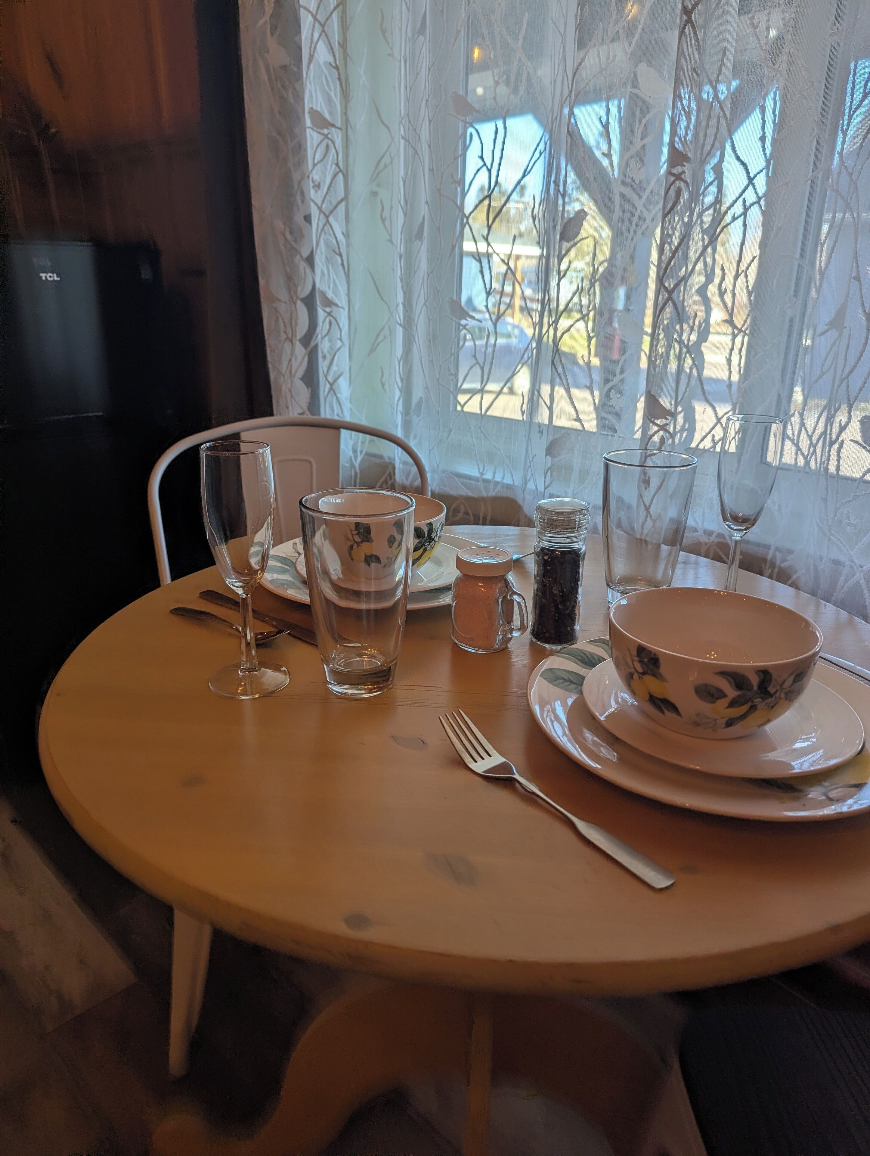 A dining table with a bowl, glass, and salt and pepper shakers.