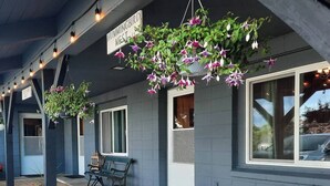 A building with a porch, hanging flower baskets, and a bench. - Feather Nest Inn (Grand Marais)