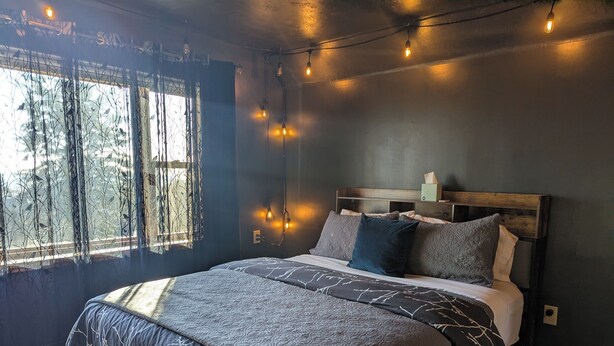 A bedroom with a large bed, a wooden headboard, and string lights. - Feather Nest Inn (Grand Marais)