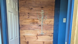 A wooden door with a metal coat rack, a doormat, and a patterned rug. - Feather Nest Inn (Grand Marais)