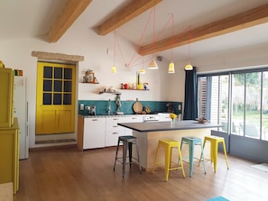 A modern kitchen with wooden beams, a yellow door, and a large window. - Unique House in the Luberon with an Above-Ground Pool   (Robion)
