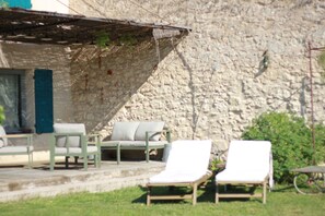 A stone wall with a covered seating area and lounge chairs. - Unique House in the Luberon with an Above-Ground Pool   (Robion)