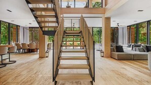 A spacious interior with a central staircase, large windows, and a modern design. - Luxury 5Br Villa with Private Pool (Playa del Carmen)