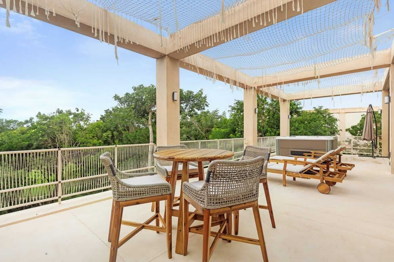 An outdoor patio with wicker furniture, a hot tub, and a view of greenery.