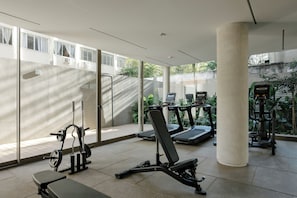 Une salle de sport équipée de divers appareils, notamment des tapis de course, un banc de développé couché et un support à squats.