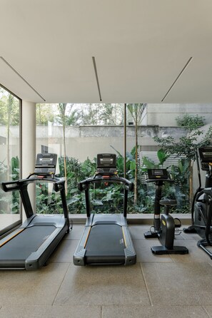 Ein Fitnessbereich mit drei nebeneinander angeordneten Laufbändern, einem Ergometer und einem Rudergerät.