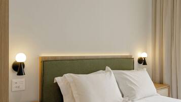 A hotel room with a bed, two bedside tables, an air conditioner, and a wall-mounted light fixture.