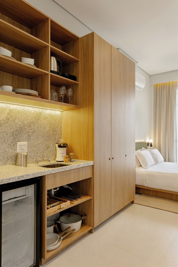 A compact kitchen with wooden cabinets, a built-in sink, and a refrigerator. - Aloe Casa Jardins (São Paulo)
