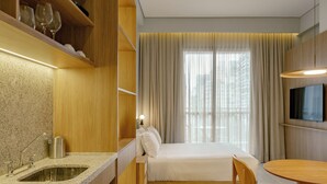 Et moderne hotelværelse med tekøkken, seng, spisebord og TV.
