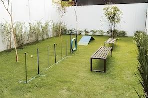 A well-maintained outdoor area with a grassy lawn, a small play structure, and two wooden benches. - SOMA PERDIZES 908 (São Paulo)
