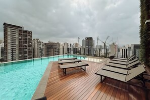 A rooftop pool area with lounge chairs and a city skyline view. - SOMA PERDIZES 908 (São Paulo)