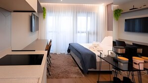 A modern bedroom with a bed, a desk, and a TV. - SOMA PERDIZES 908 (São Paulo)