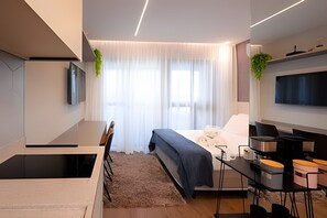 A modern bedroom with a bed, a desk, and a TV. - SOMA PERDIZES 908 (São Paulo)