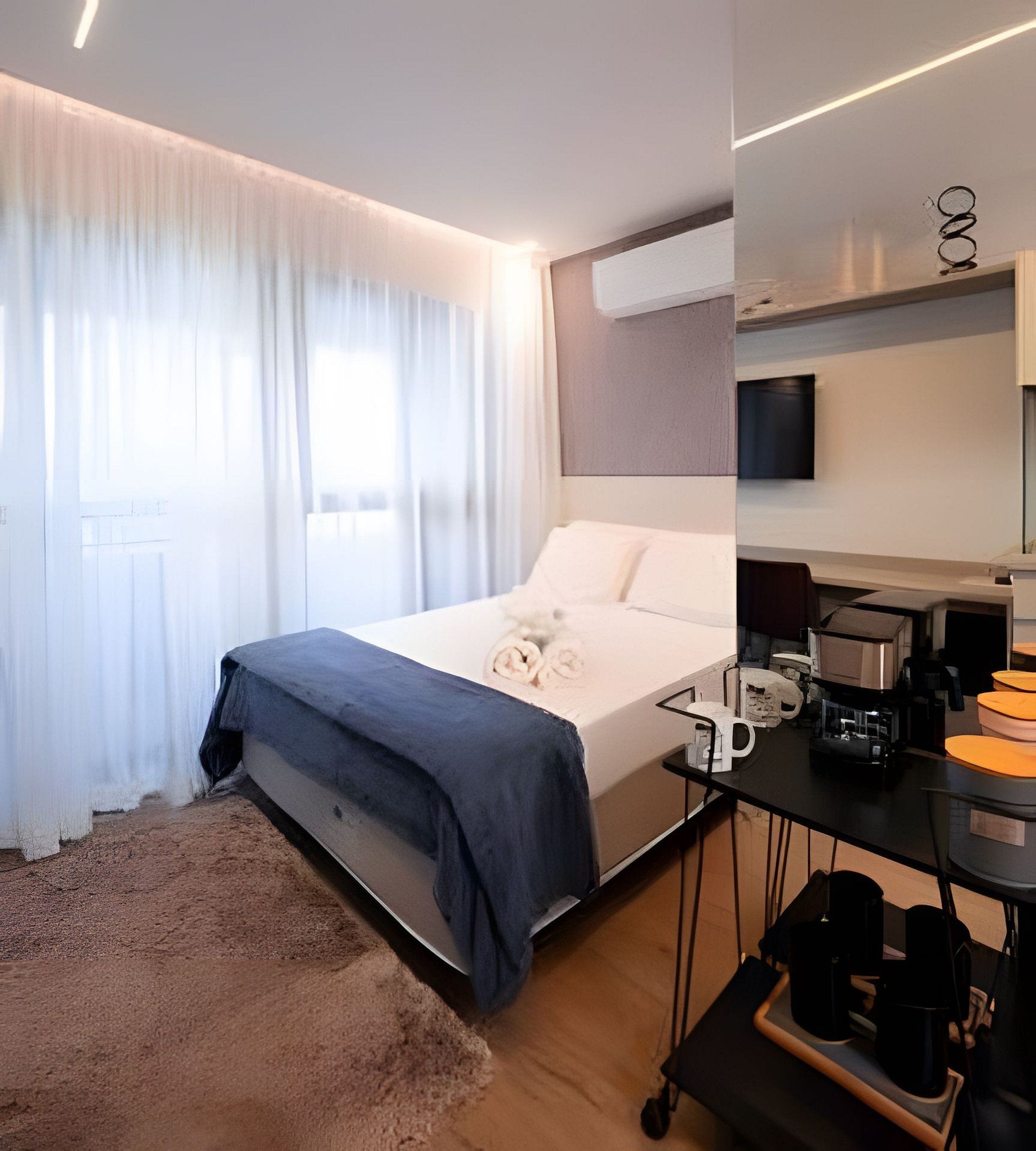 Une chambre d’hôtel moderne équipée d’un lit, d’un bureau avec une machine à café et d’un téléviseur fixé au mur.